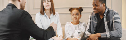 Family counseling session at home with therapist. Pshycologist showing pictures of emotions to a girL.African American father and European mother.