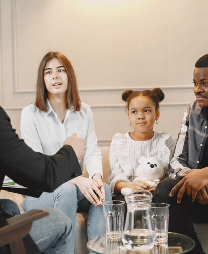 Family counseling session at home with therapist. Pshycologist showing pictures of emotions to a girL.African American father and European mother.